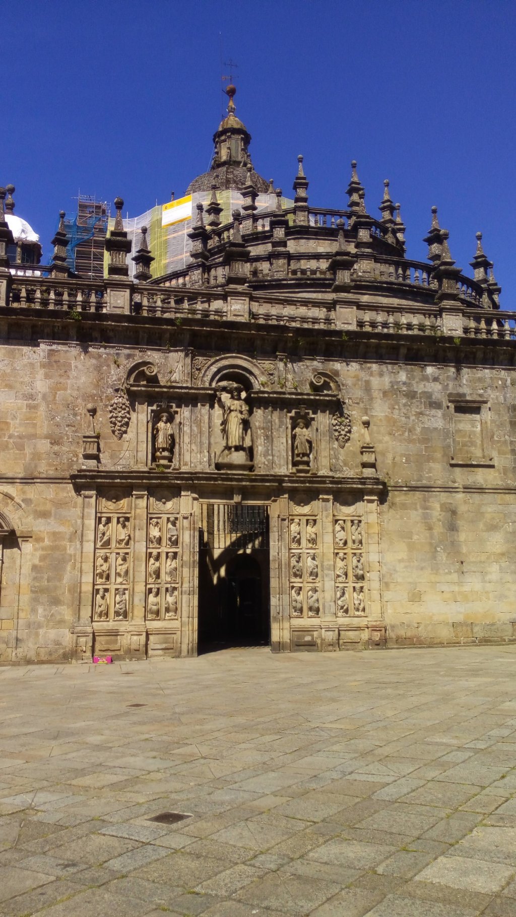 La Puerta Santa enmarcada por 24 estatuas recuperadas del coro románico del Maestro Mateo, en el S. XVI. En su parte superior las esculturas que representan a Santiago y a sus discípulos Atanasio y Teodoro